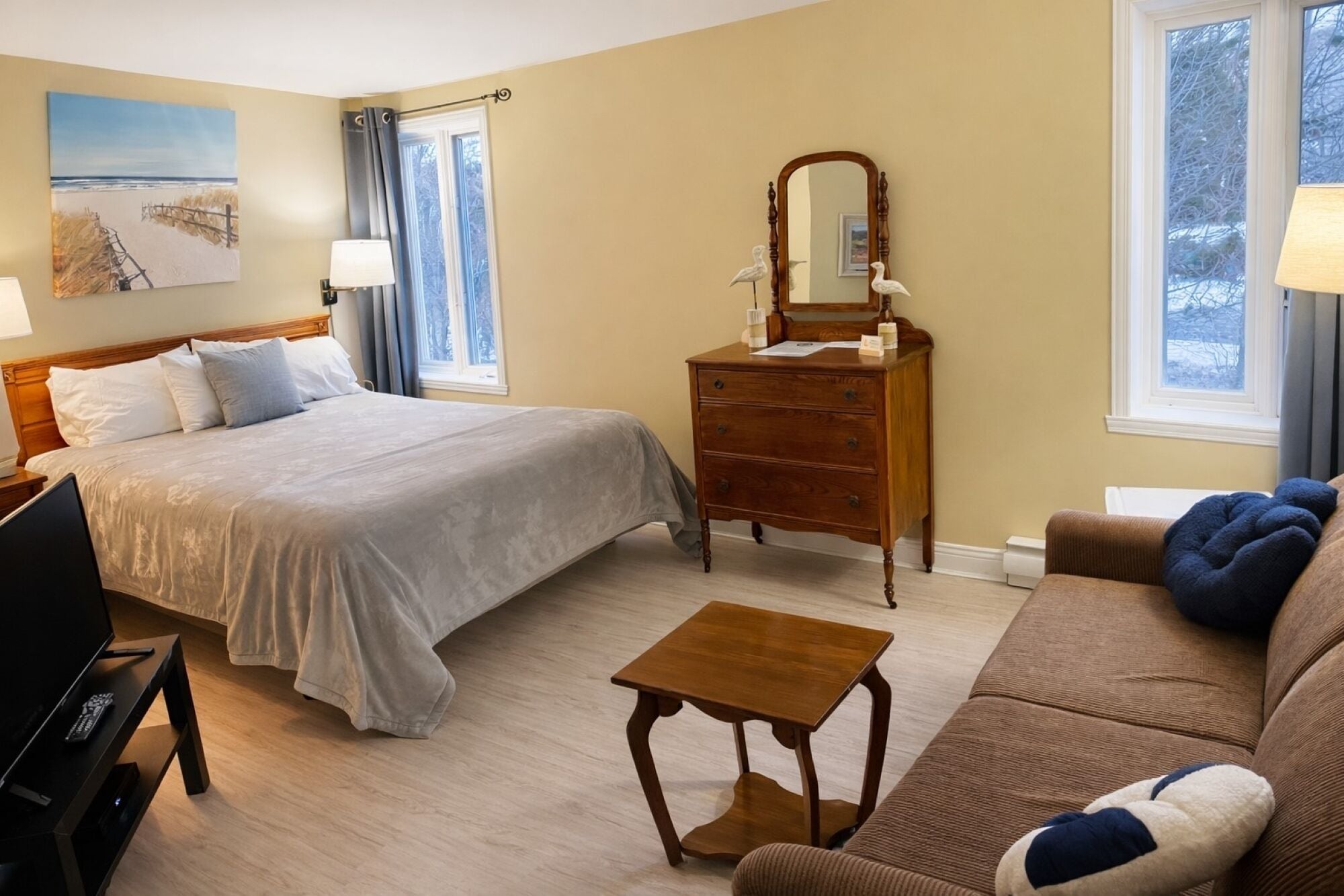 A hotel room with a bed, dresser, mirror, and a small table.