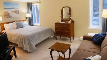 A hotel room with a bed, dresser, mirror, and a small table.