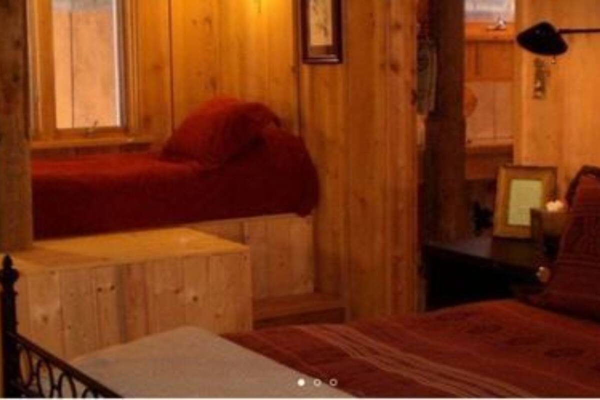 A wooden cabin room with a bunk bed, a small desk, and a window.