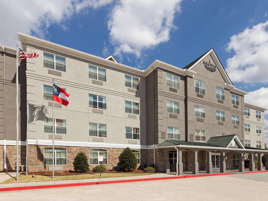 Un hotel de varios pisos con techo plano, entrada cubierta y fachada de ladrillo.