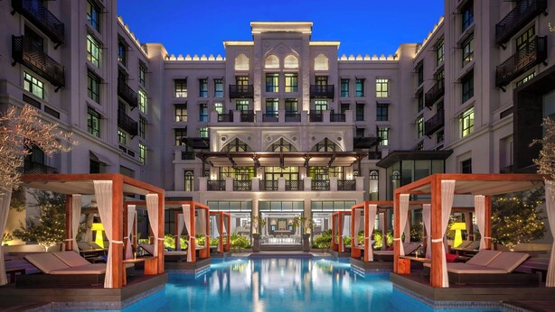 A hotel with a large pool, multiple balconies, and a well-lit facade. - Hotel Boulevard, Autograph Collection (Dubai)
