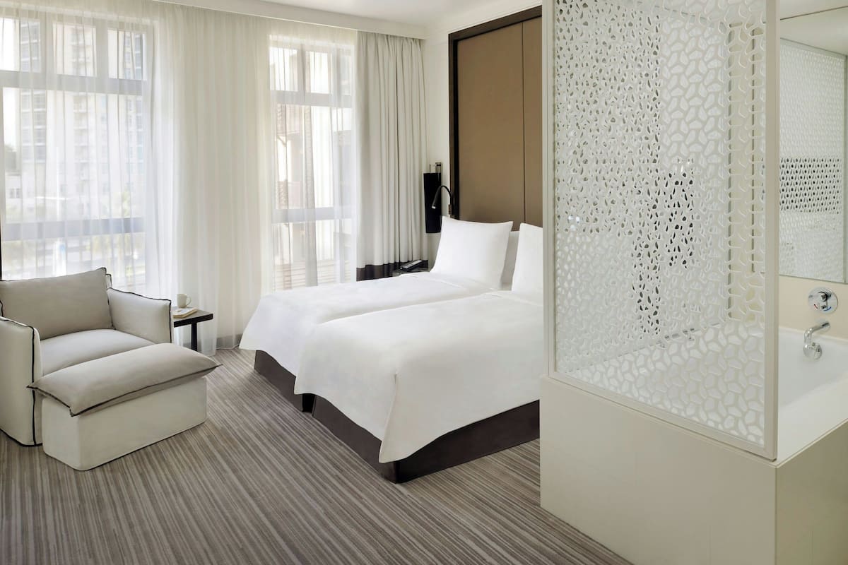 A hotel room with two beds, a sofa, a small table, and a decorative screen.
