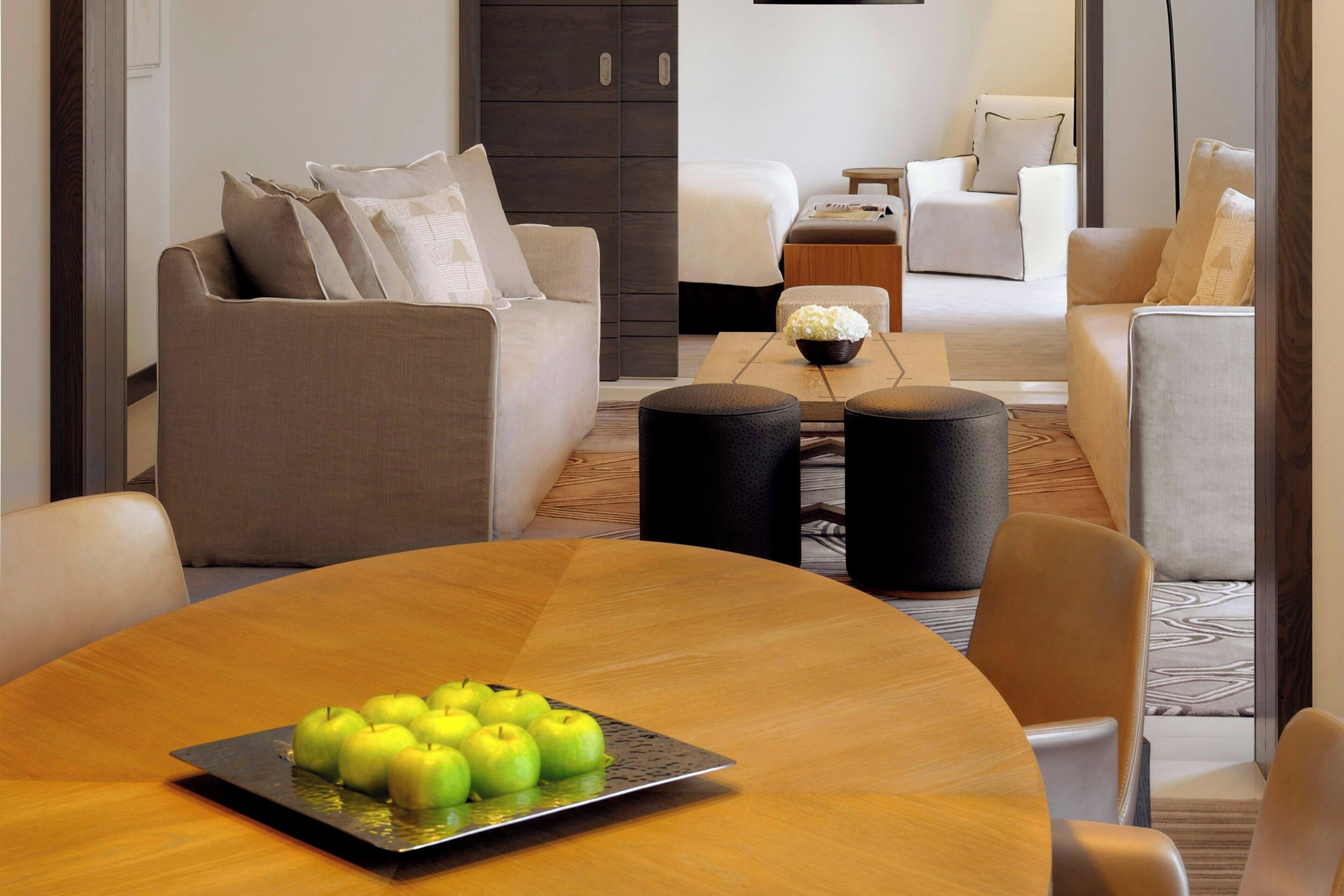 A modern living room with a round wooden table, a sofa, and a coffee table with apples.