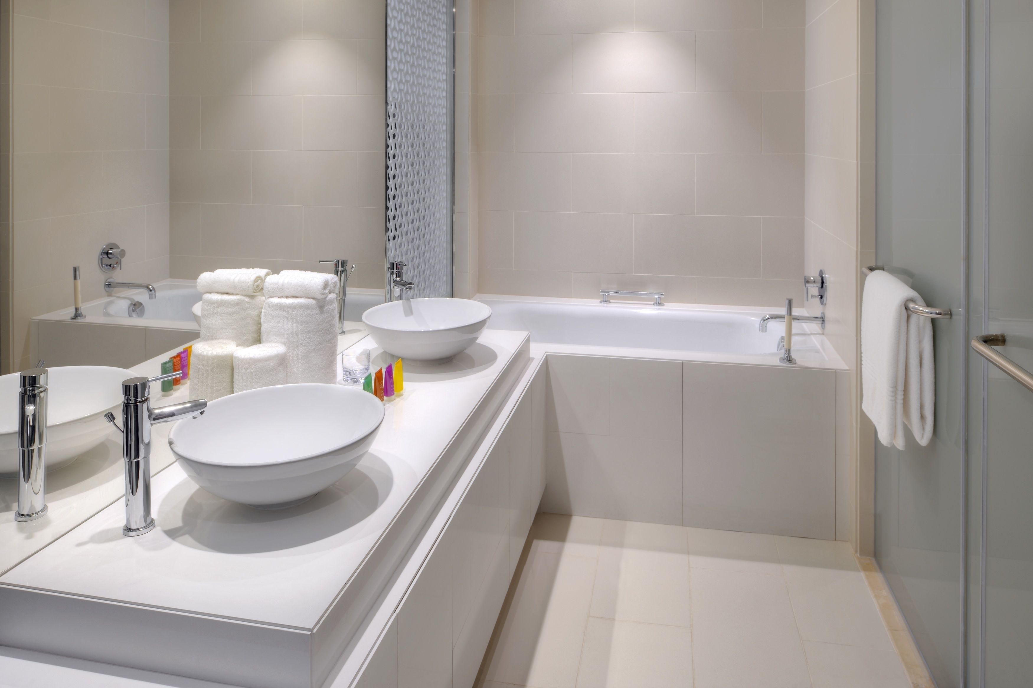 A modern bathroom with a double sink, a large bathtub, and a glass shower enclosure.