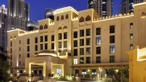 A hotel with a central courtyard, multiple floors, and a prominent tower in the background. - Hotel Boulevard, Autograph Collection (Dubai)