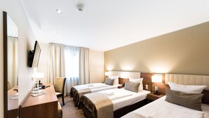 Ein Hotelzimmer mit zwei Betten, einem Schreibtisch, einem Stuhl und einem großen Spiegel.