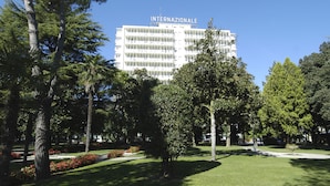 A building with "INTERNAZIONALE" on the facade, surrounded by a well-maintained park with various trees and flower beds. - Hotel Terme Internazionale (Abano Terme)