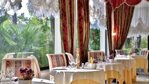 A dining area with tables set for a meal, chairs, and a view of greenery outside. - Hotel Terme Internazionale (Abano Terme)