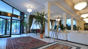 A spacious lobby with a large red carpet, potted plants, a reception area, and a staircase. - Hotel Terme Internazionale (Abano Terme)