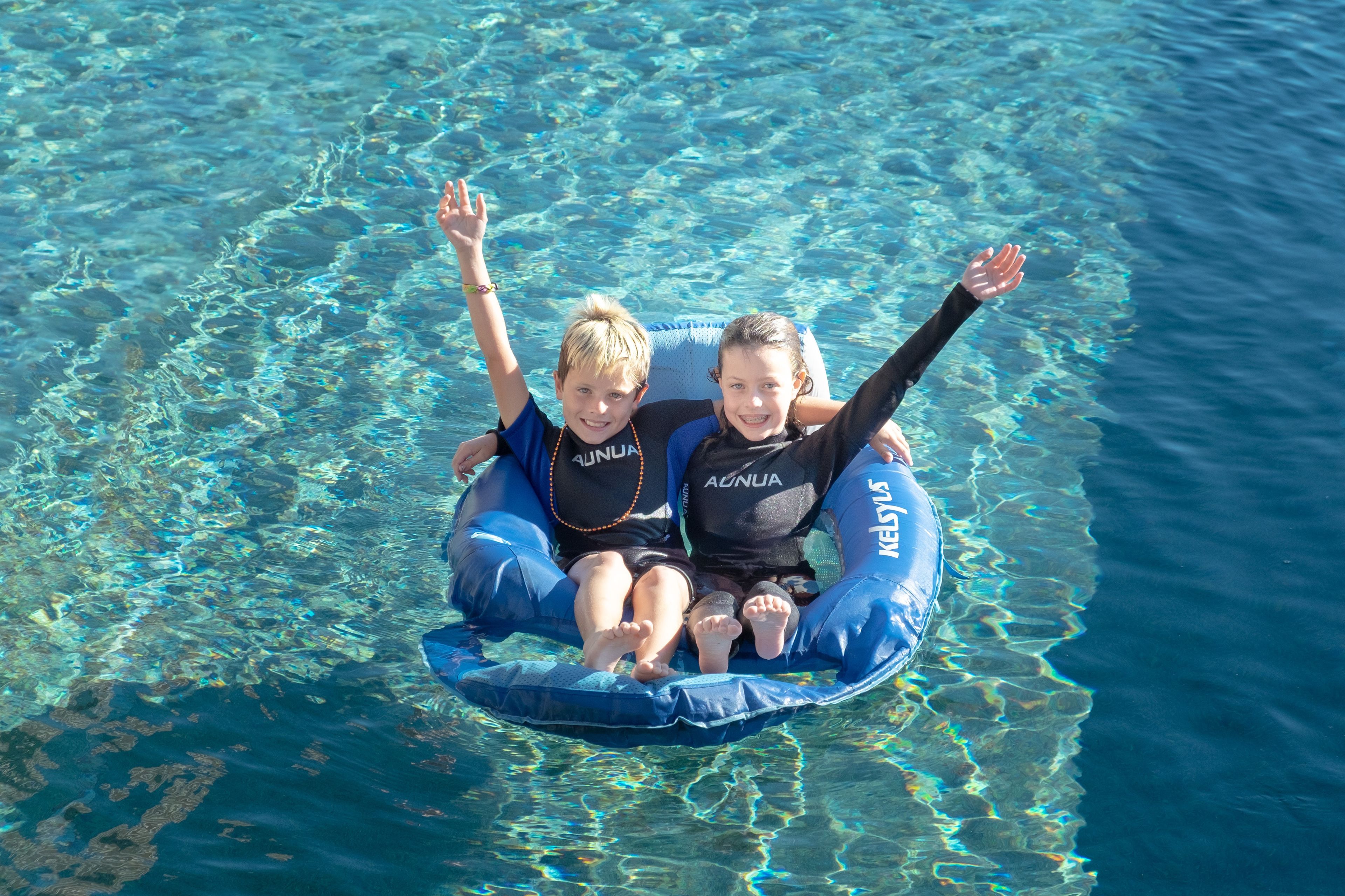 Two people on a blue inflatable raft in clear water.