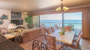 Un comedor amplio con vistas al océano, que cuenta con una mesa grande, asientos cómodos y detalles decorativos como una lámpara con forma de estrella de mar y obras de arte.