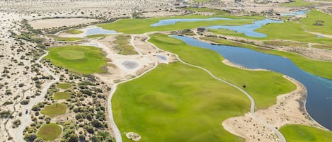 A golf course with multiple greens, water hazards, and a desert landscape.