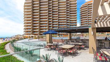 A resort with a pool area, outdoor seating, and a large building in the background.