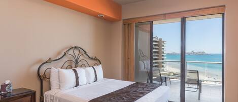Une chambre à coucher comprenant un lit, une table de chevet, un ventilateur de plafond et un balcon avec vue sur la plage et l’océan.