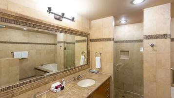 A bathroom with a large mirror, two sinks, a shower, and a towel rack.