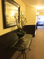 A glass-top table with a potted plant, a mirror, and a sofa in the background.