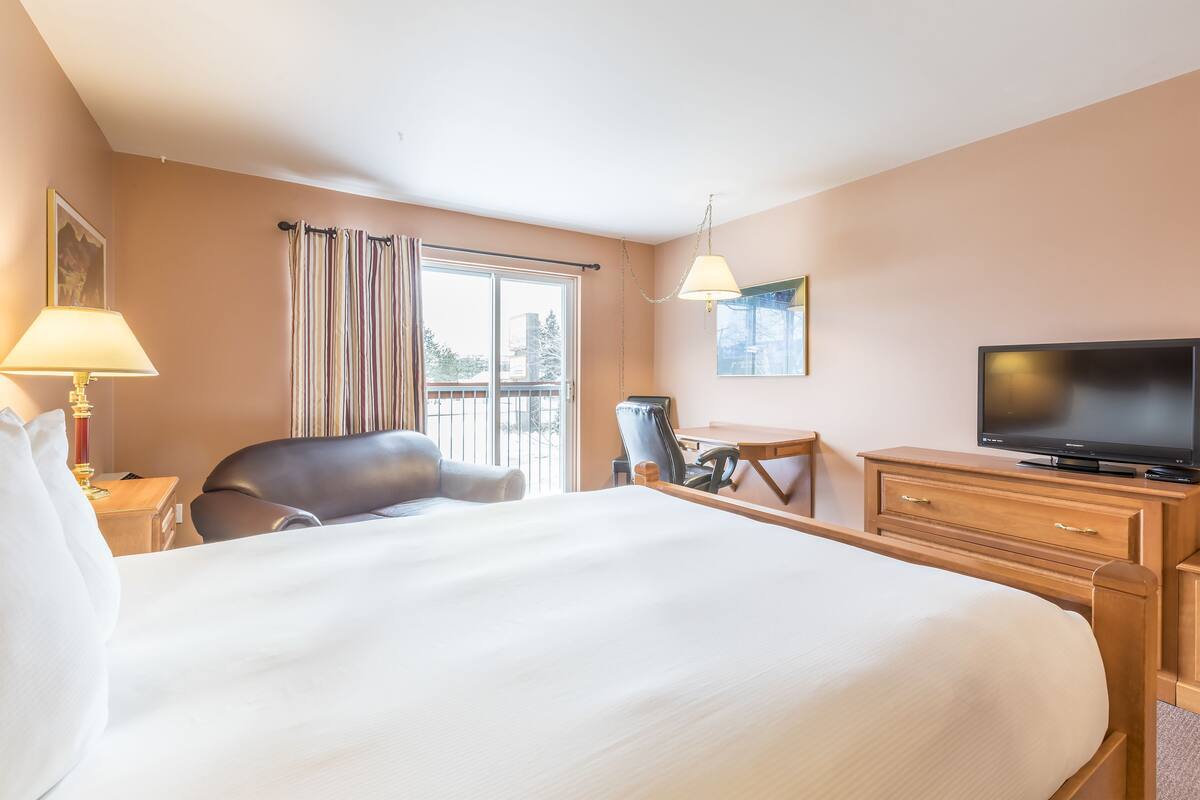 Hotelkamer met een groot bed, een bureau, een stoel, een televisie en een raam met gordijnen.