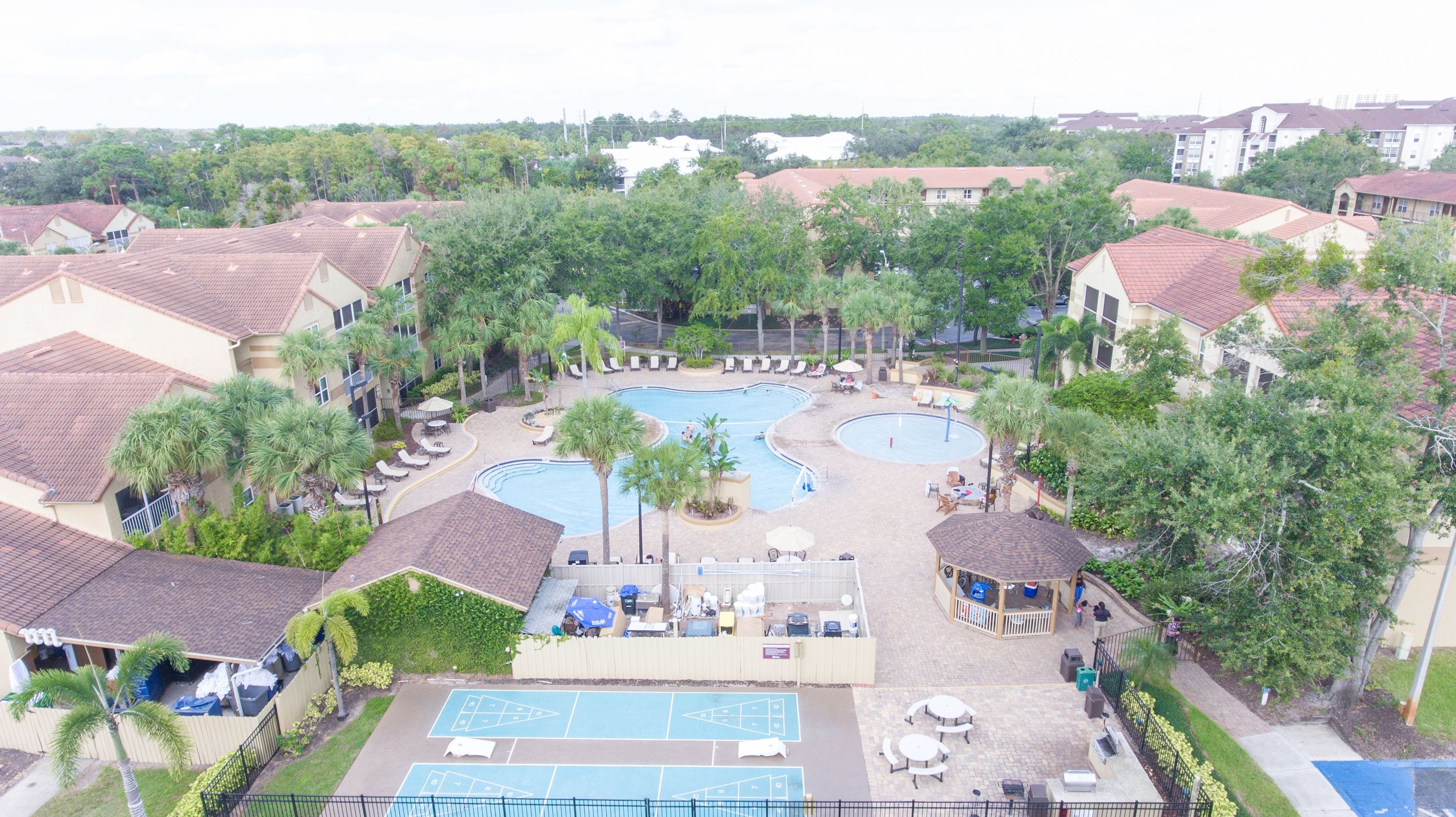 A resort with multiple swimming pools, lounge areas, and a tennis court.
