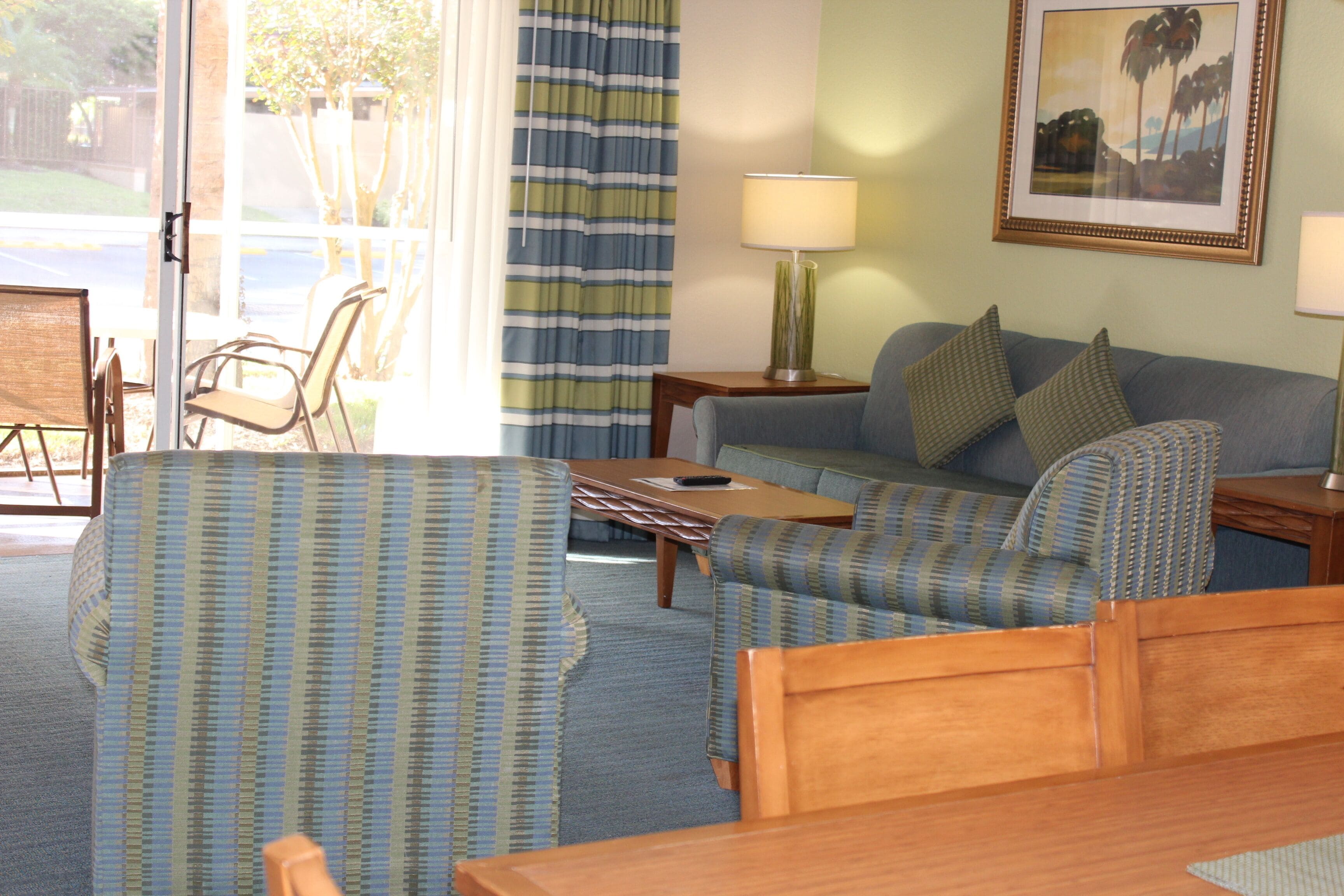 A room with a bed, a sofa, a chair, a small table, and a lamp.