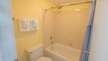 A bathroom with a toilet, bathtub, and shower.