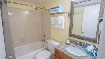 A bathroom with a bathtub, toilet, sink, and a mirror.