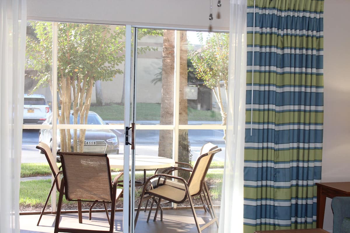 Ein Zimmer mit einer Glastür, die auf eine Terrasse mit Tisch und Stühlen führt.