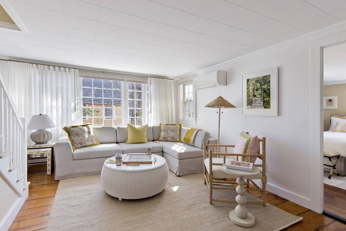 A spacious living room with a large sectional sofa, a round coffee table, and a wicker chair.