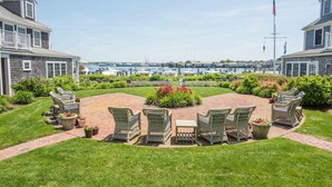 A patio with wicker furniture and a flower bed, overlooking a marina with boats. - White Elephant Hotel (Nantucket)