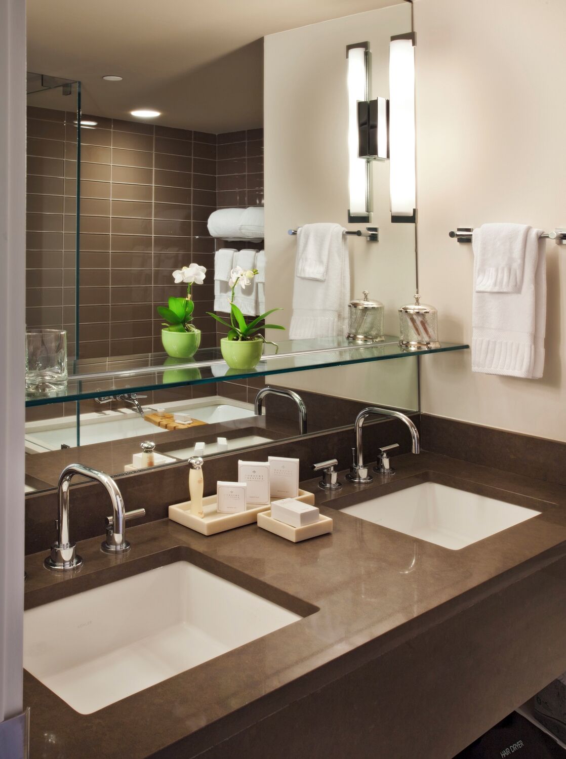 Un bagno moderno con due lavandini, box doccia in vetro e un grande specchio.
