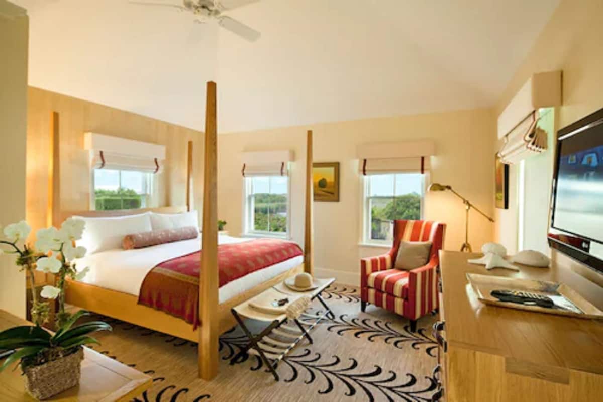 A hotel room with a bed, a TV, a desk, a chair, and a window with a view.