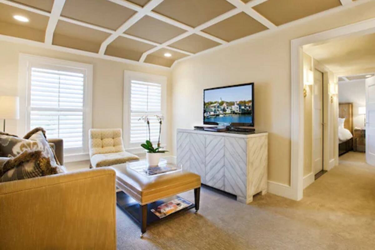 A living room with a sofa, armchair, coffee table, TV, and a white cabinet.