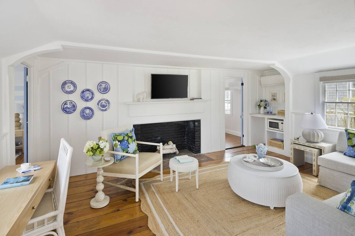 A living room with a fireplace, white walls, and blue decorative plates.