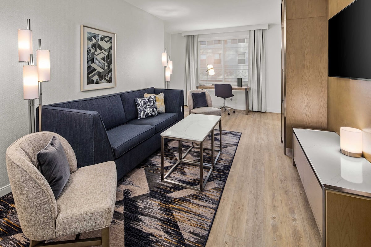 A modern living room with a sofa, armchair, coffee table, and a flat-screen TV.