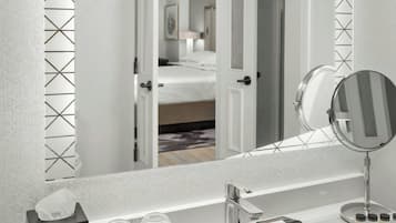 Une salle de bain avec un grand miroir, un lavabo et une boîte de mouchoirs.