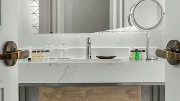 Une salle de bain moderne avec un meuble-lavabo blanc, un miroir et une étagère en bois où sont pliées des serviettes.