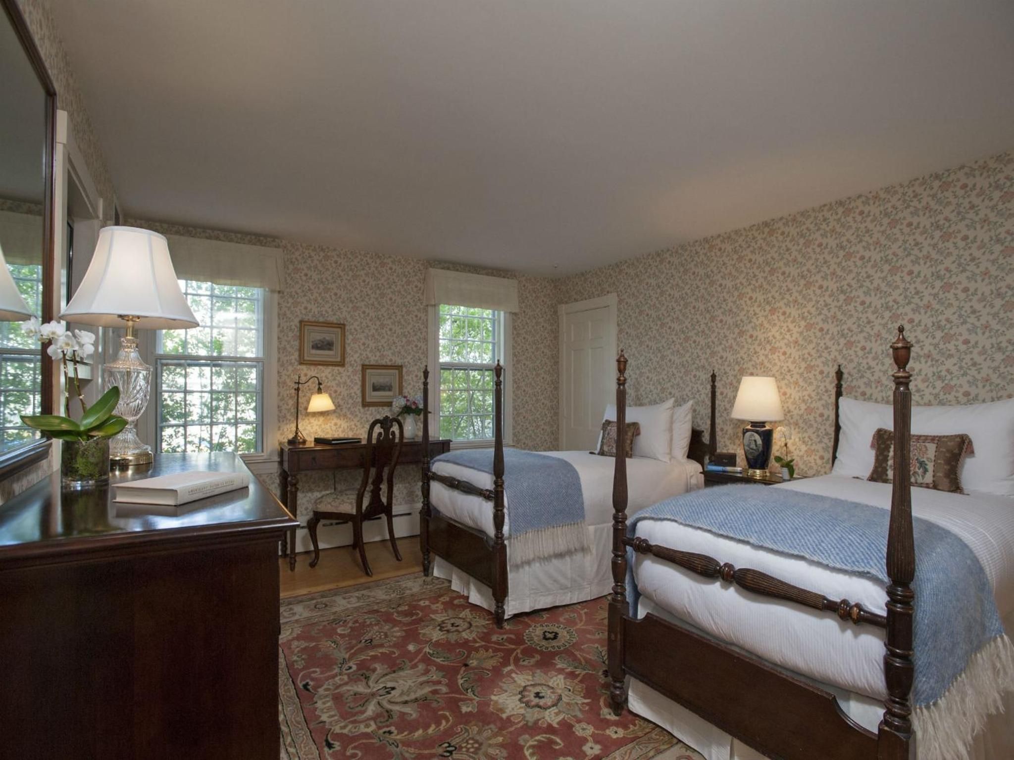 A traditional bedroom with two single beds, a desk, and a chair.