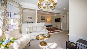 A spacious living room with a white sofa, a round coffee table, and a chandelier. - Jared Coffin House (Nantucket)