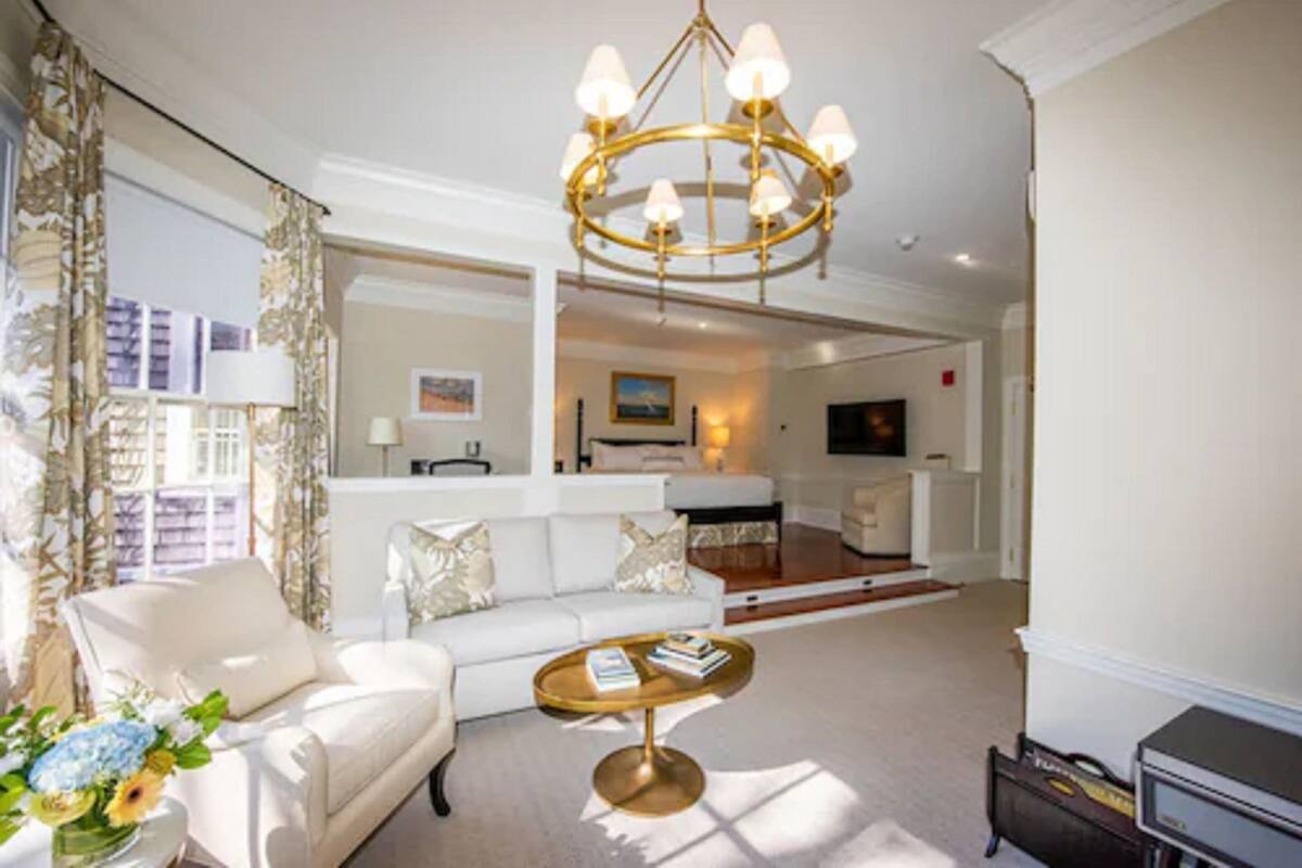 A spacious living room with a white sofa, a round coffee table, and a chandelier.