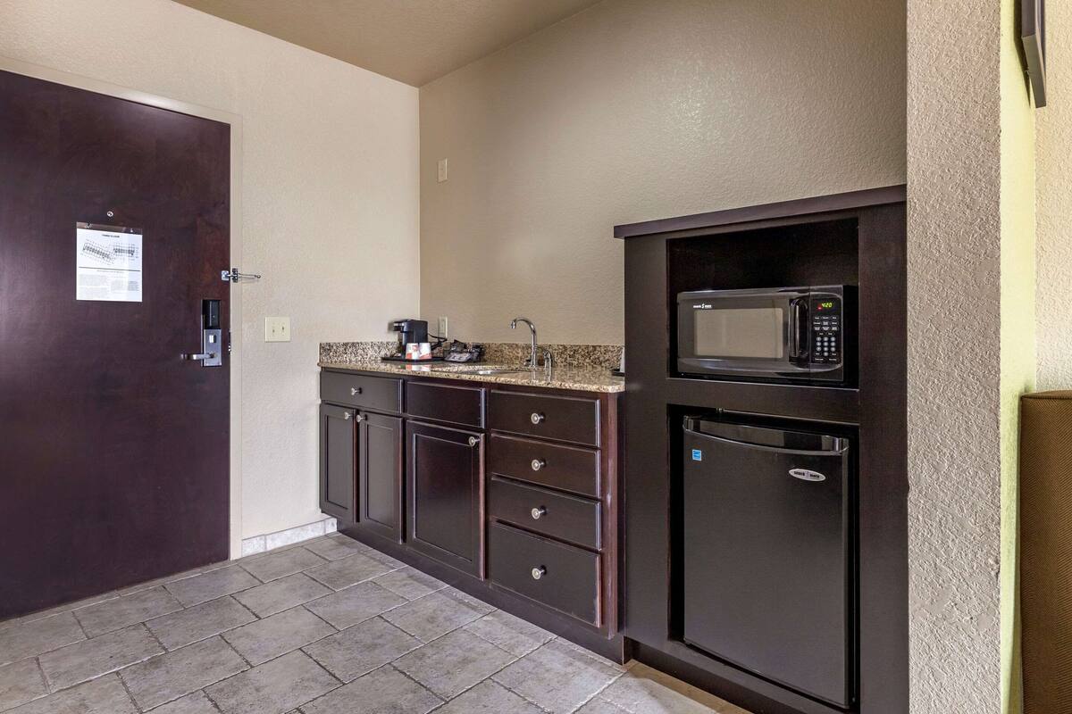 A compact kitchen with dark cabinetry, a built-in microwave, and a coffee maker.