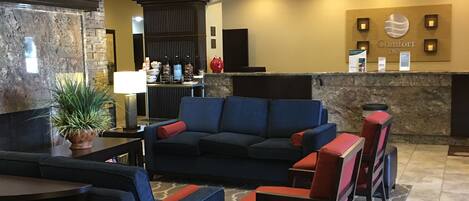 A lobby with a reception desk, seating area, and a stone accent wall.