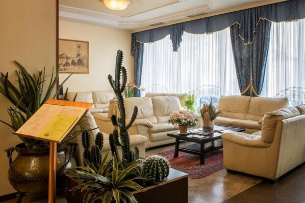 A living room with two beige sofas, a coffee table, and various cacti and plants.