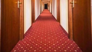 A hotel hallway with a red carpet and wooden doors on both sides. - Hotel Everest (Trento)