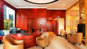A conference room with a wooden desk, leather chairs, a printer, and a fireplace.