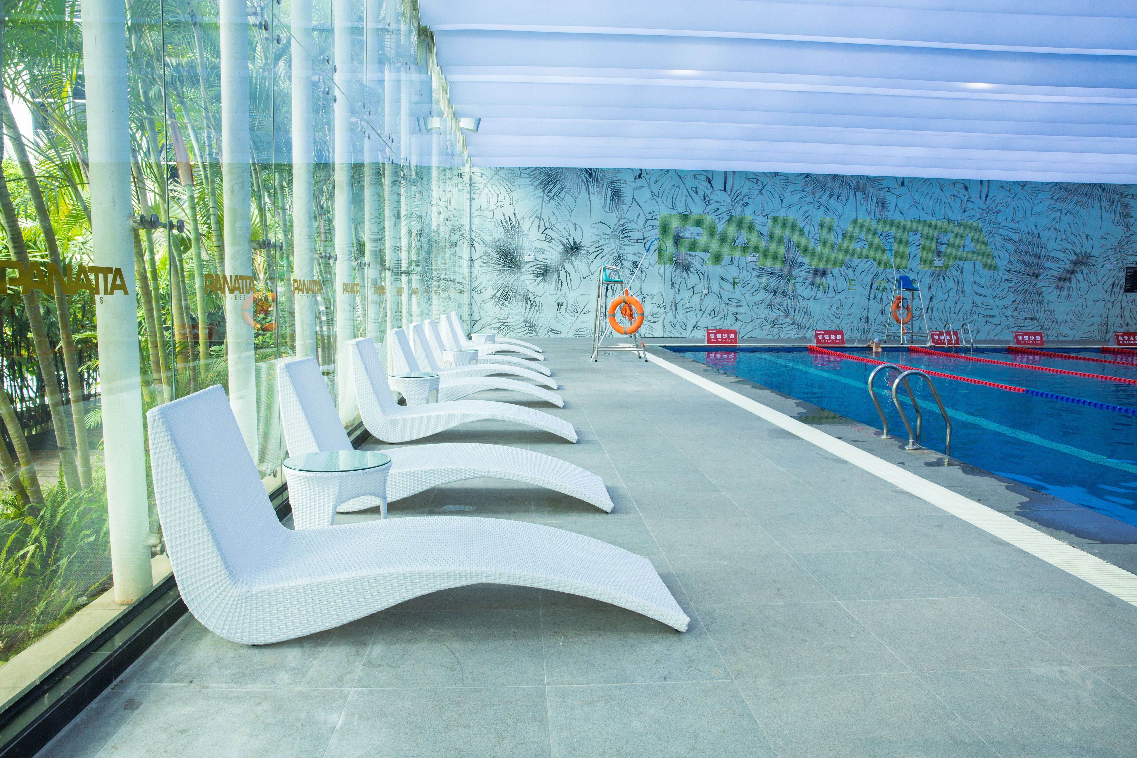 A modern indoor pool area with lounge chairs and a lifeguard stand.