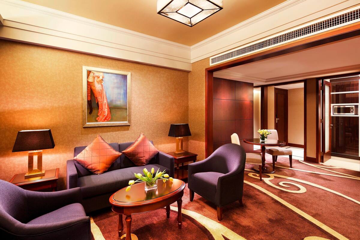 Eine Lobby mit einer Couch, Sesseln, einem Couchtisch und einem Gemälde an der Wand.