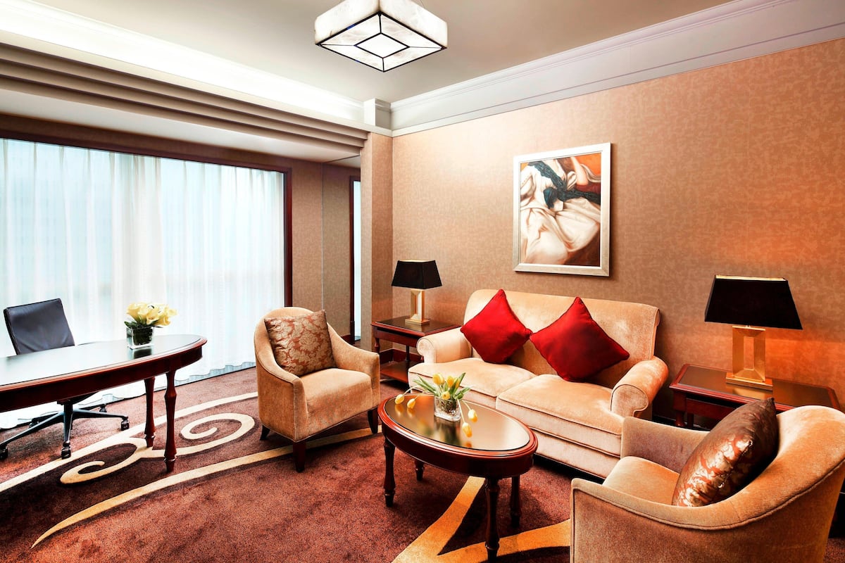 Ein modernes Hotelzimmer mit einer Couch, Sesseln, einem Couchtisch und einem Schreibtisch.