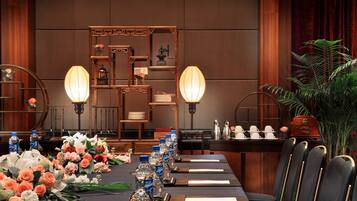 A formal dining table set with floral arrangements, water bottles, and place settings in a room with wooden paneling and traditional decor.