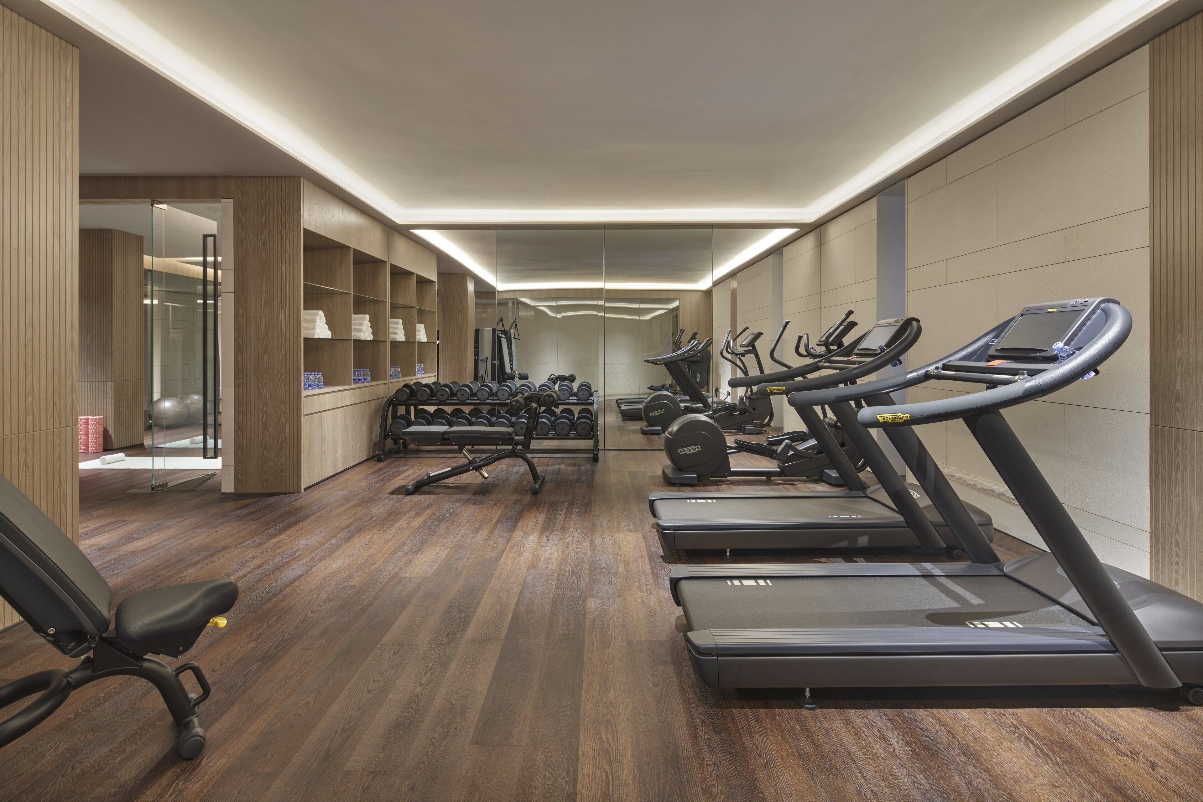 A modern gym with treadmills, dumbbells, and a rowing machine.