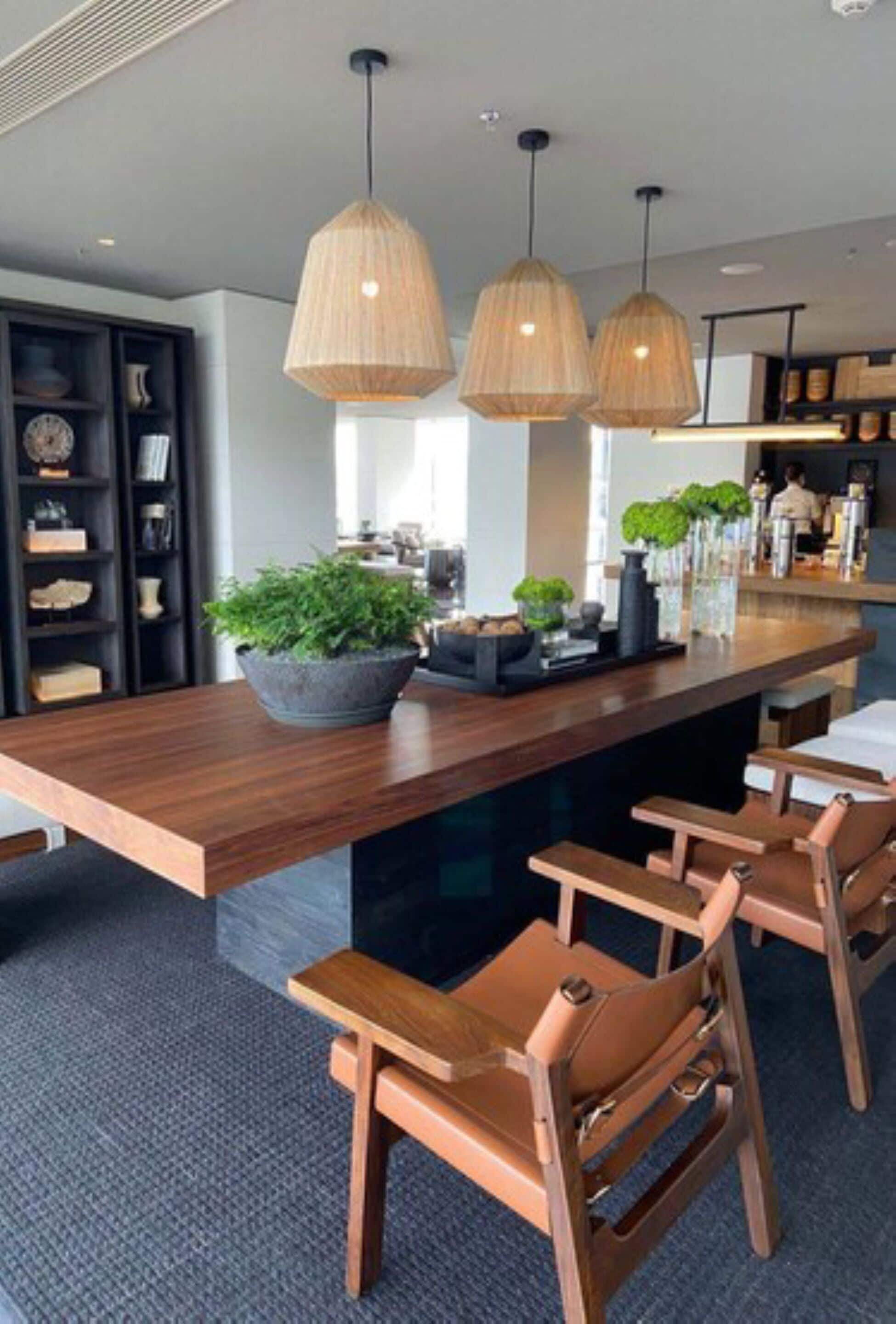 A modern kitchen with a wooden bar, pendant lights, and bar stools.