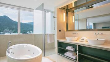 A modern bathroom with a bathtub, two sinks, and a large mirror.